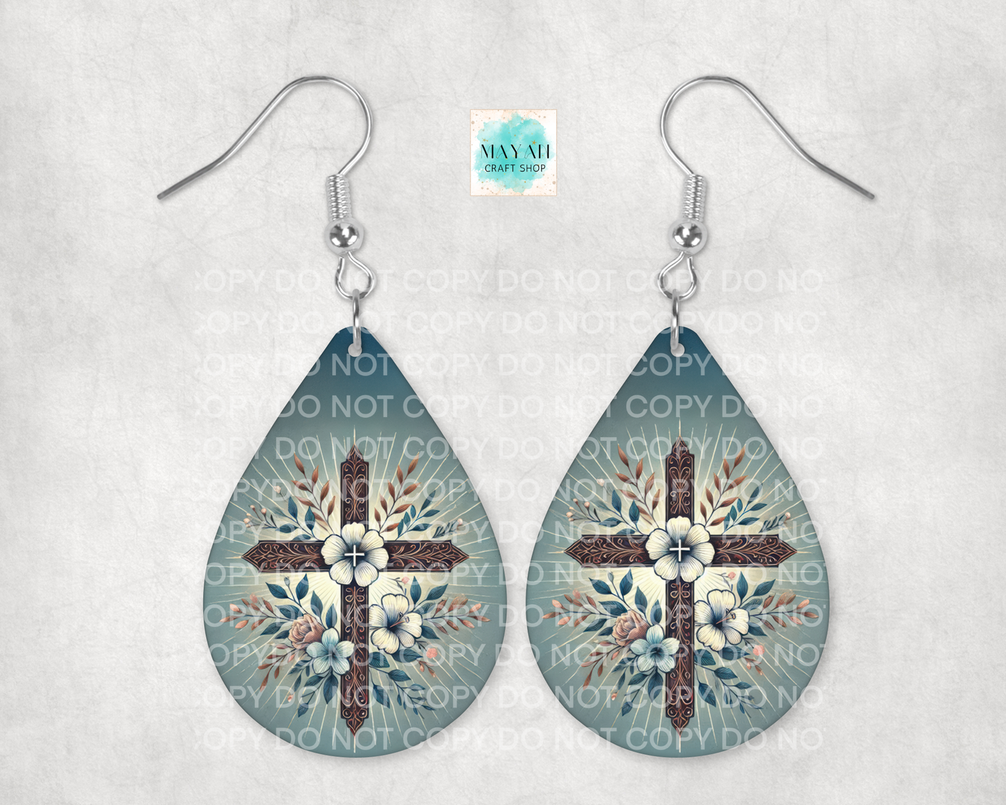 Teardrop-shaped earrings with floral cross design on a light gray background
