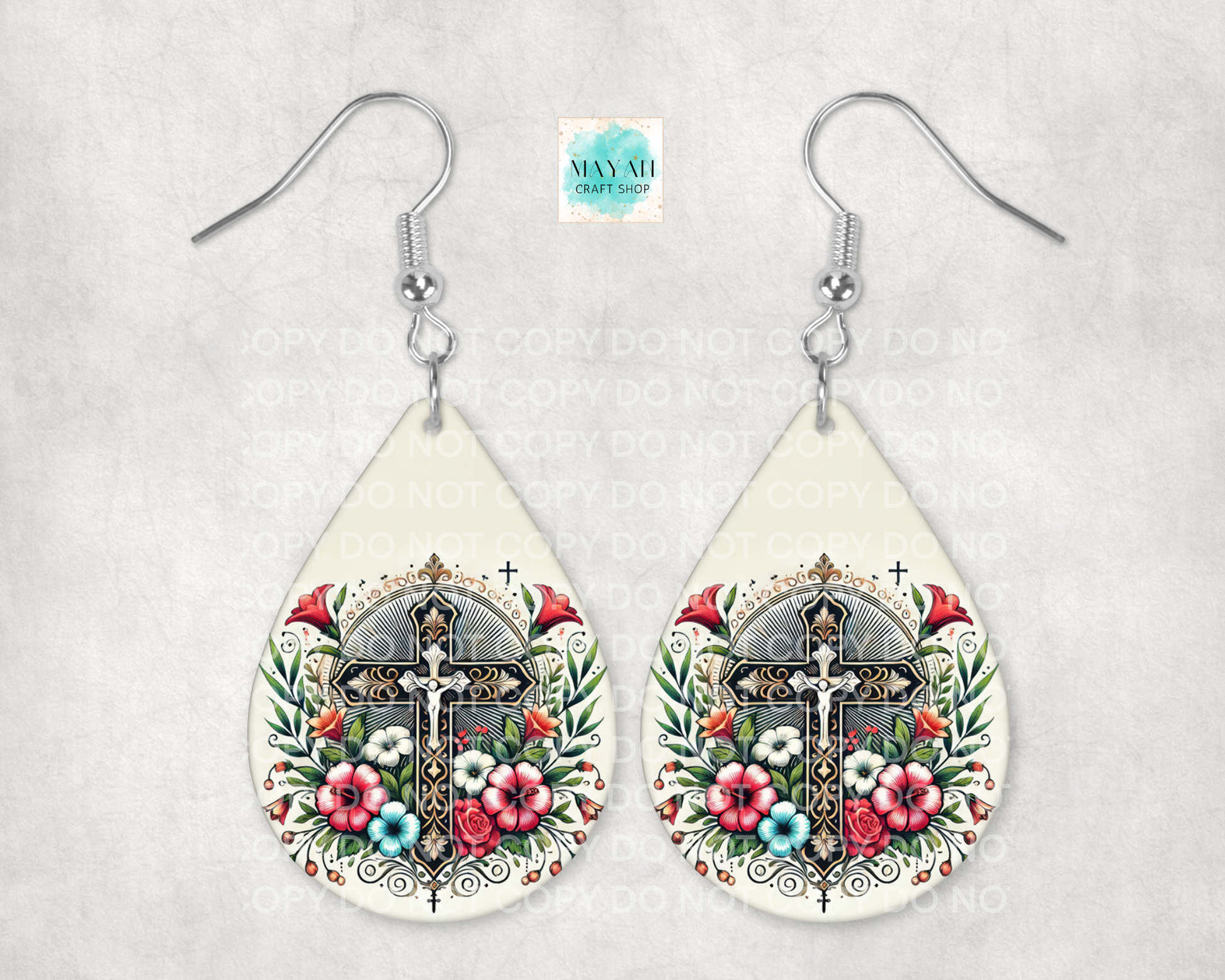 Teardrop-shaped earrings with floral and cross design on a light gray background
