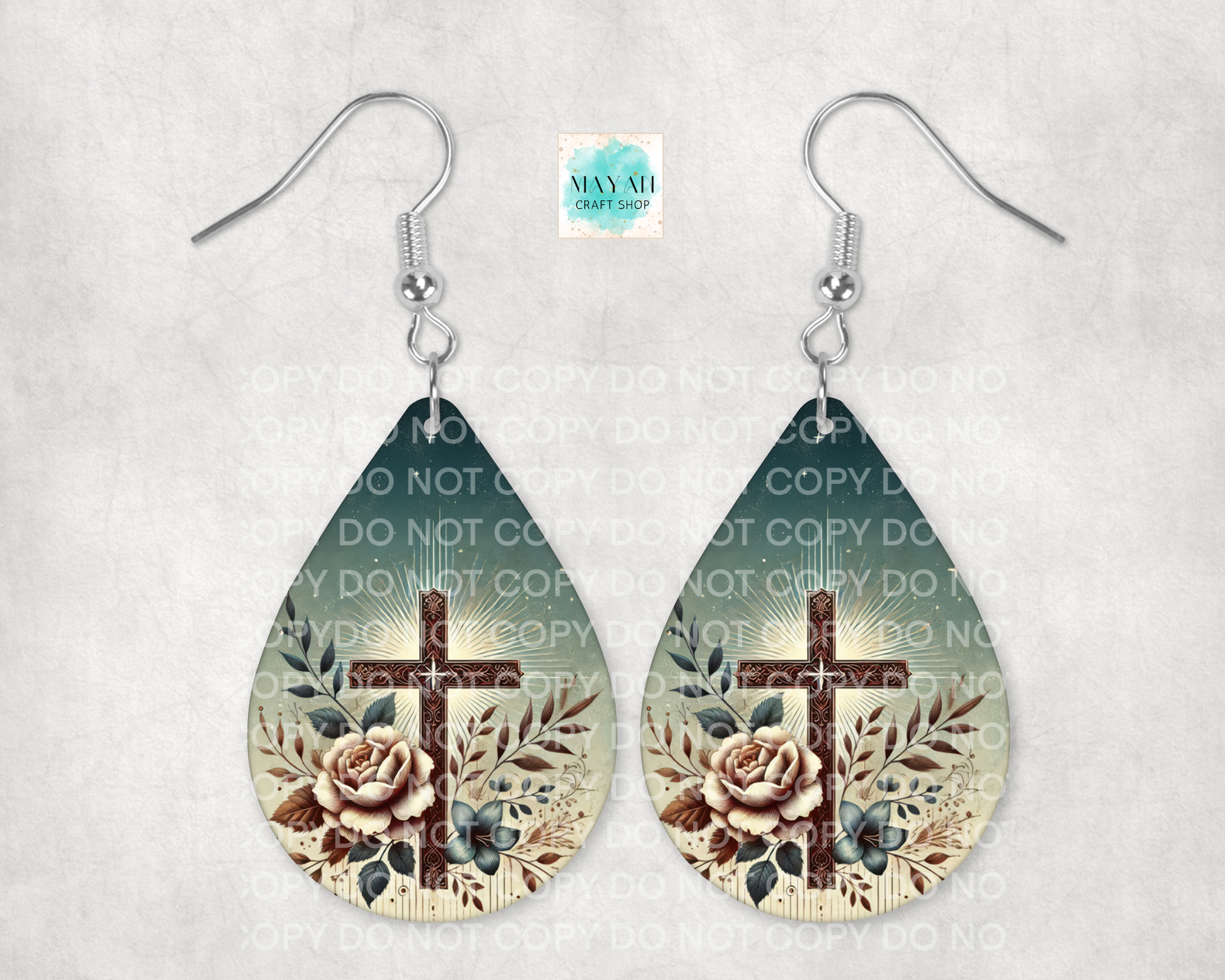 Teardrop-shaped earrings with cross and floral design on a light gray background