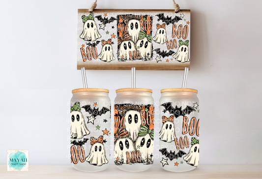 Three frosted glass mason jars with bamboo lids are displayed below a matching rectangular wooden sign featuring a Halloween ghost and bat pattern. The jars have white straws inserted, and the background is a clean white wall.