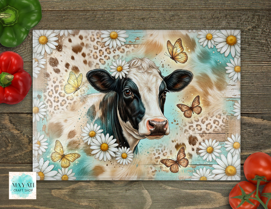 Cutting board with a cow and floral design on a wooden surface