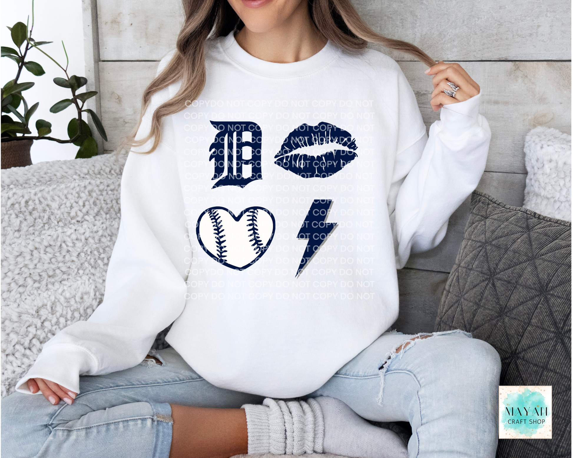 Person wearing a white sweatshirt with blue graphics sitting on a couch.