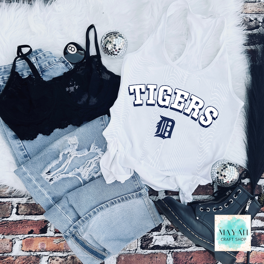 White tank top with baseball logo print, black bralette, denim shorts, and black shoes on a brick surface.