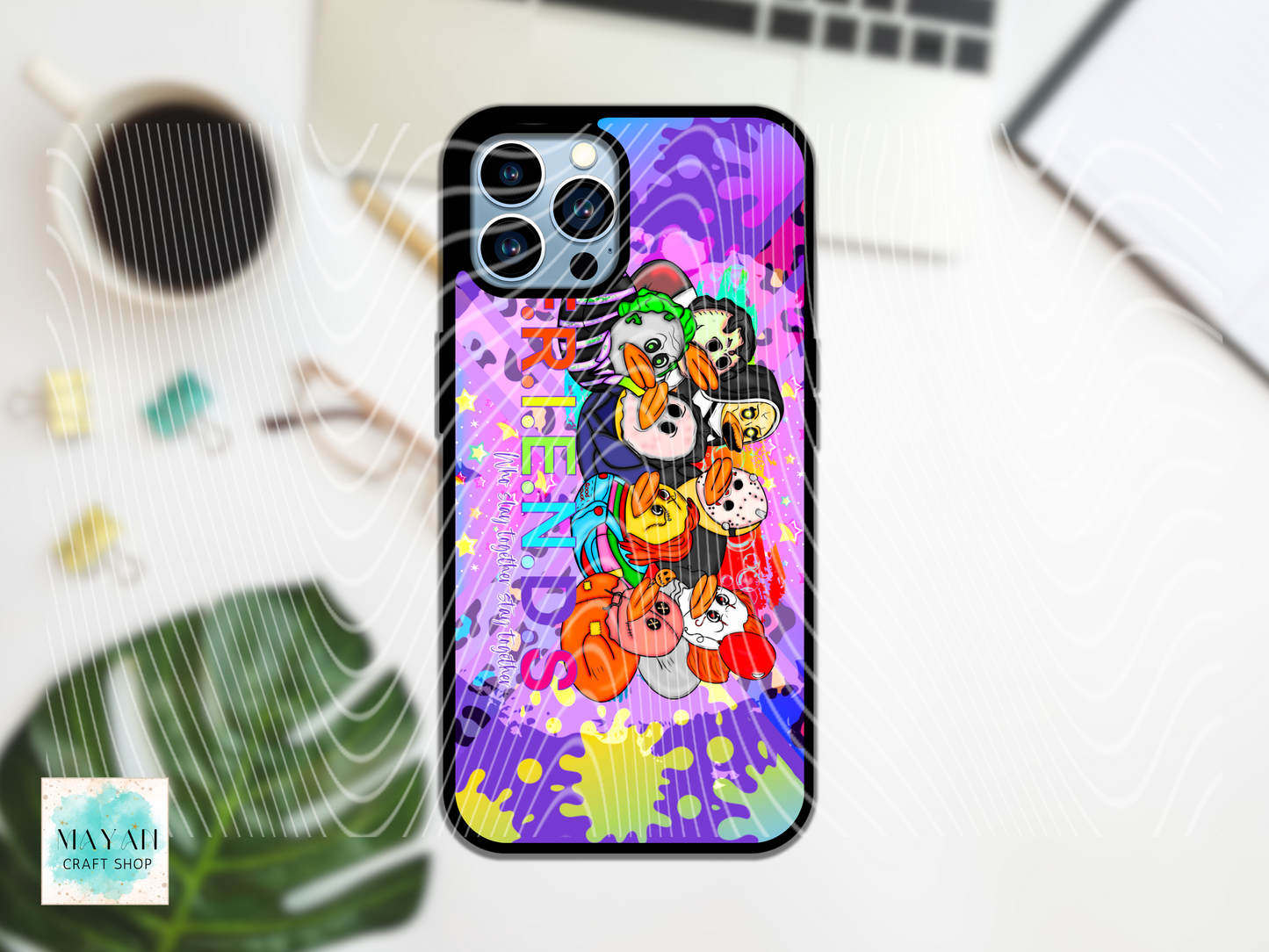 Colorful phone case with cartoon characters on a desk with a laptop and coffee cup.
