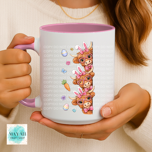Person holding a mug with cartoon cow design.