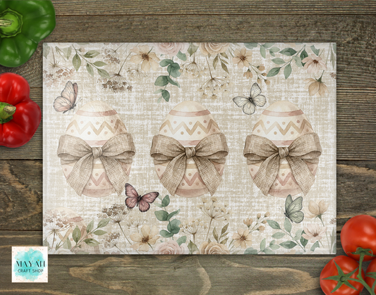Decorative cutting board with floral and butterfly design on a wooden surface with vegetables.