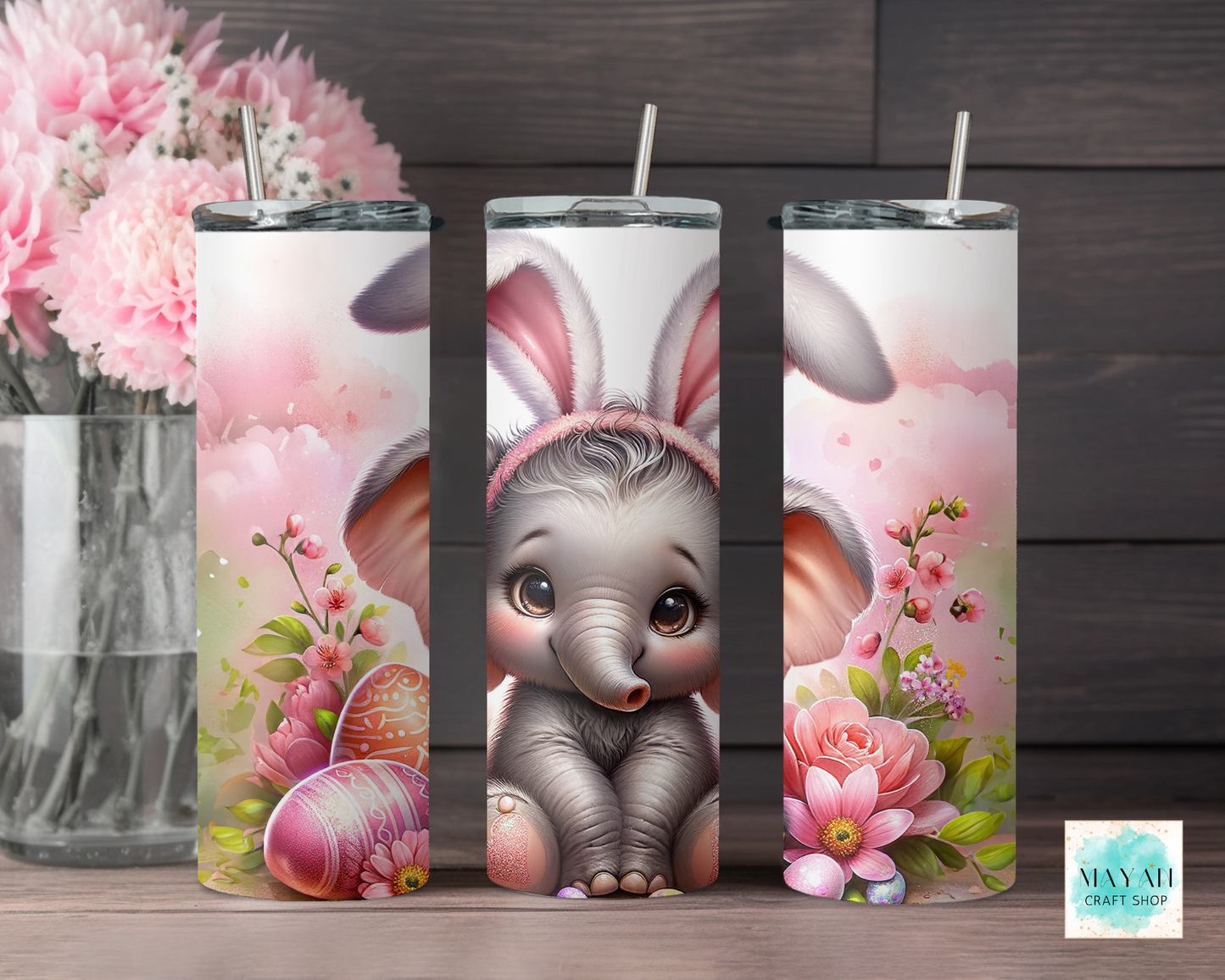 Three cylindrical tumbler with a cute elephant design and floral elements on a wooden surface.