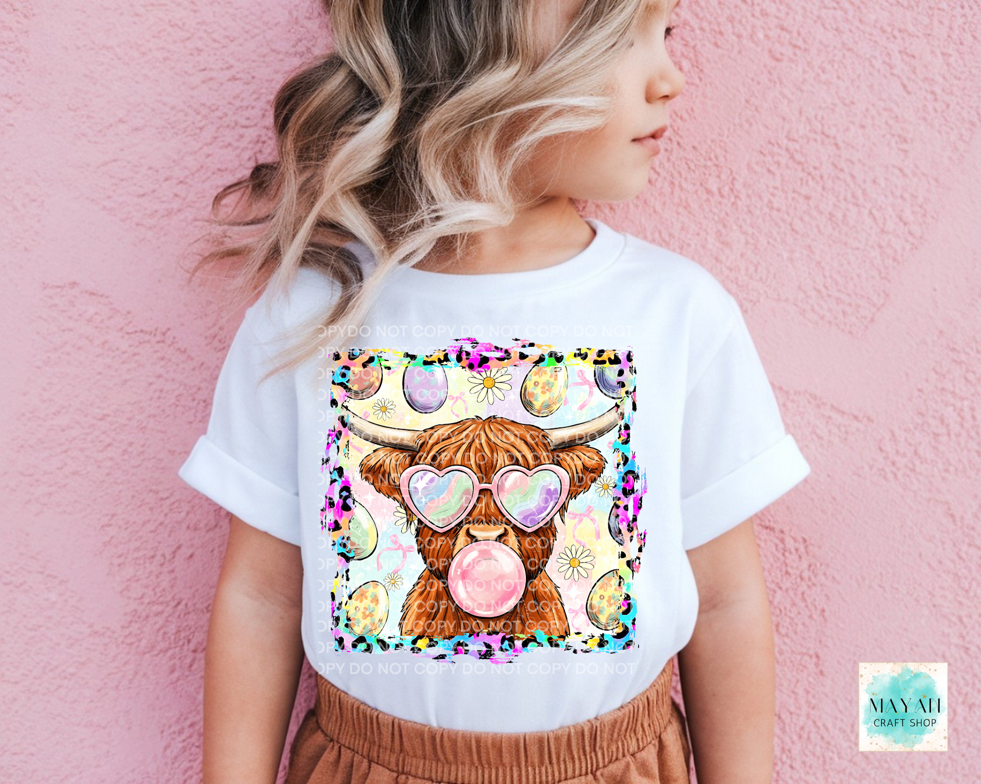 Person wearing a white t-shirt with a colorful cow design on a pink background