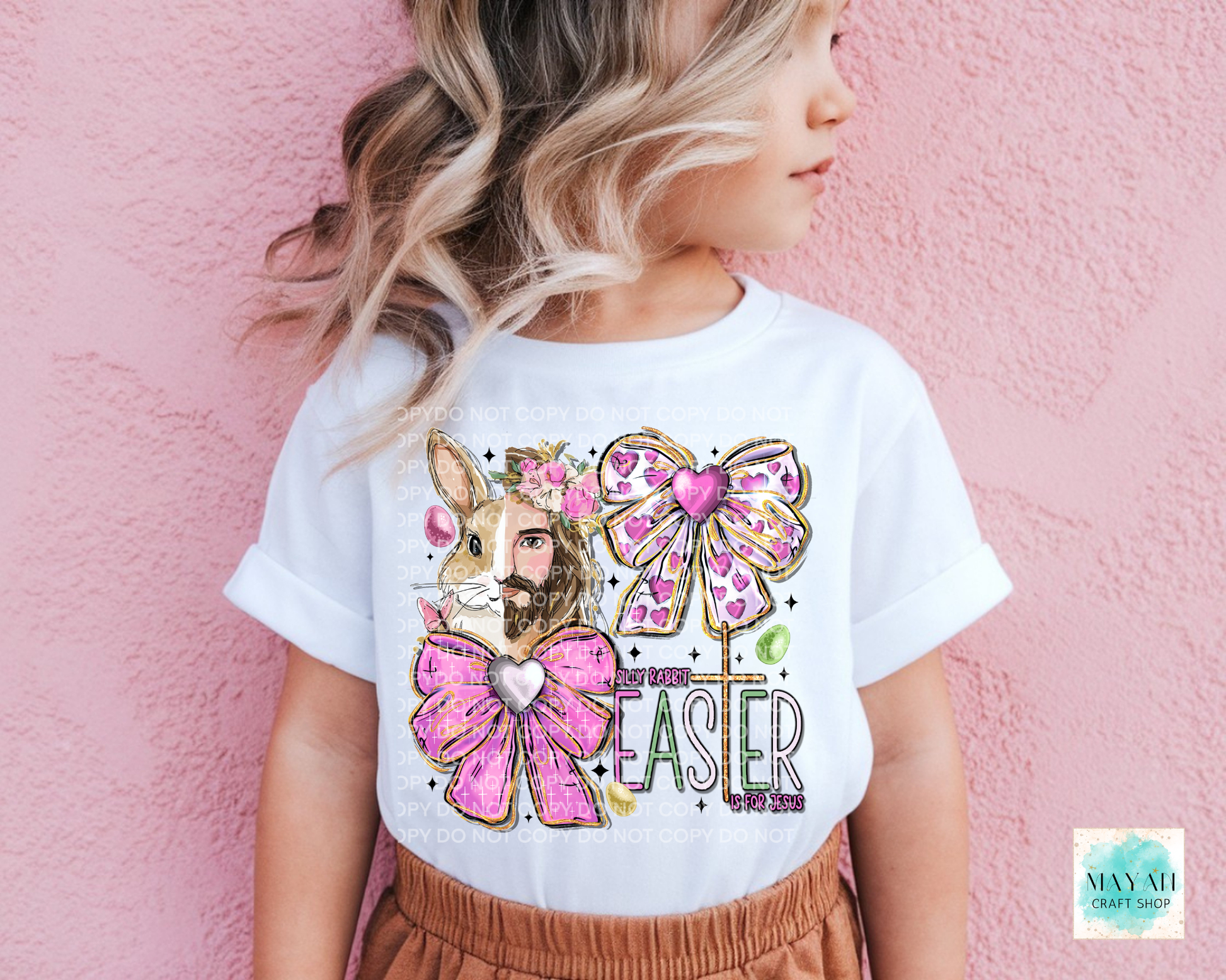Child wearing a white t-shirt with an Easter design featuring a bunny and pink bows on a pink background.