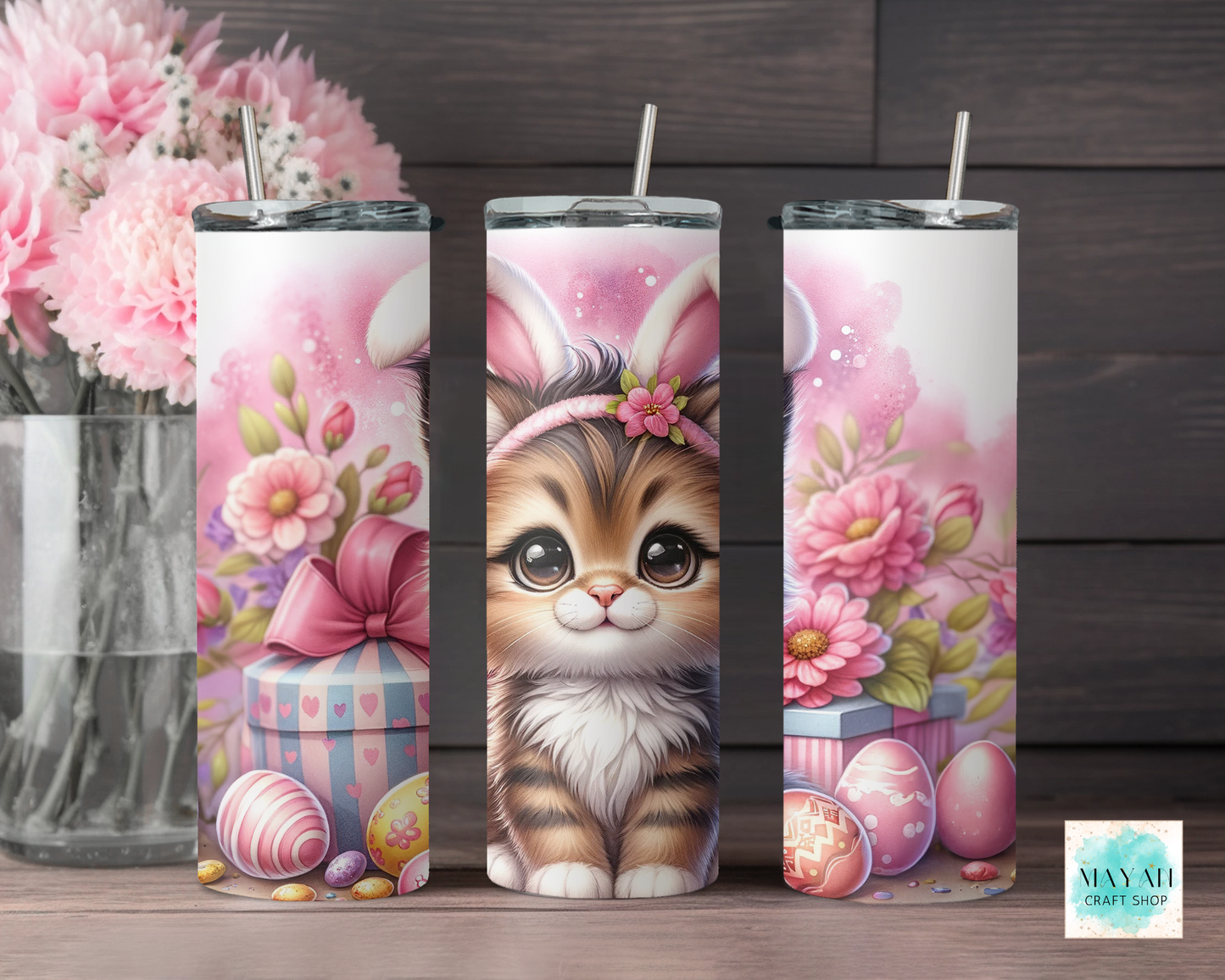 Three tumbler designs with a cat wearing bunny ears, flowers, and Easter eggs on a wooden surface.