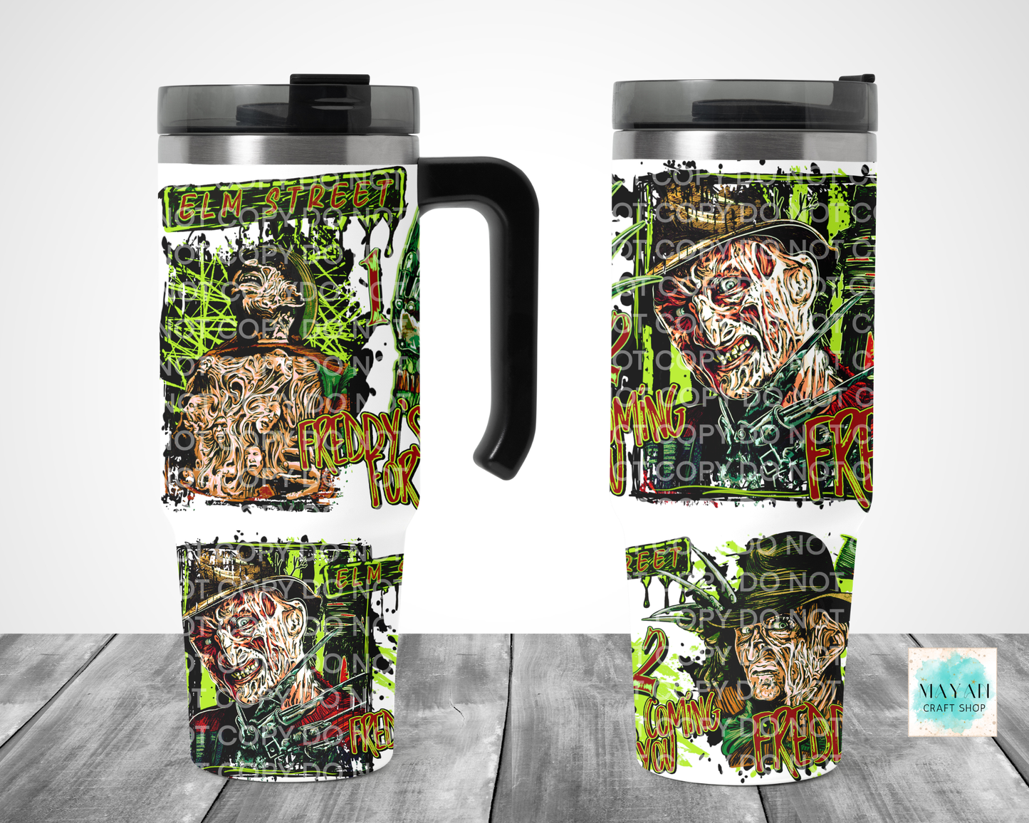 A travel mug shown from multiple angles on a gray wood floor against a white wall. The mug has a black handle and lid, with a wraparound horror-themed graphic featuring a zombie face, green graffiti-style splatters, and distressed text.