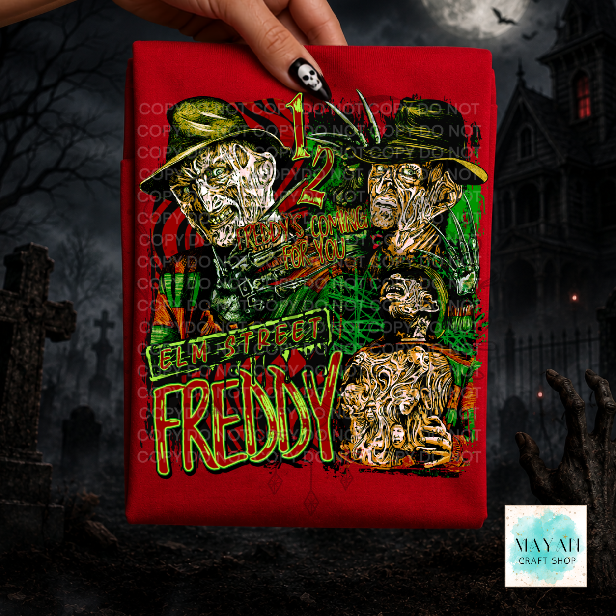 A hand holds a red graphic T-shirt with a text in green and yellow. The background is a dark, spooky graveyard scene with a haunted house.