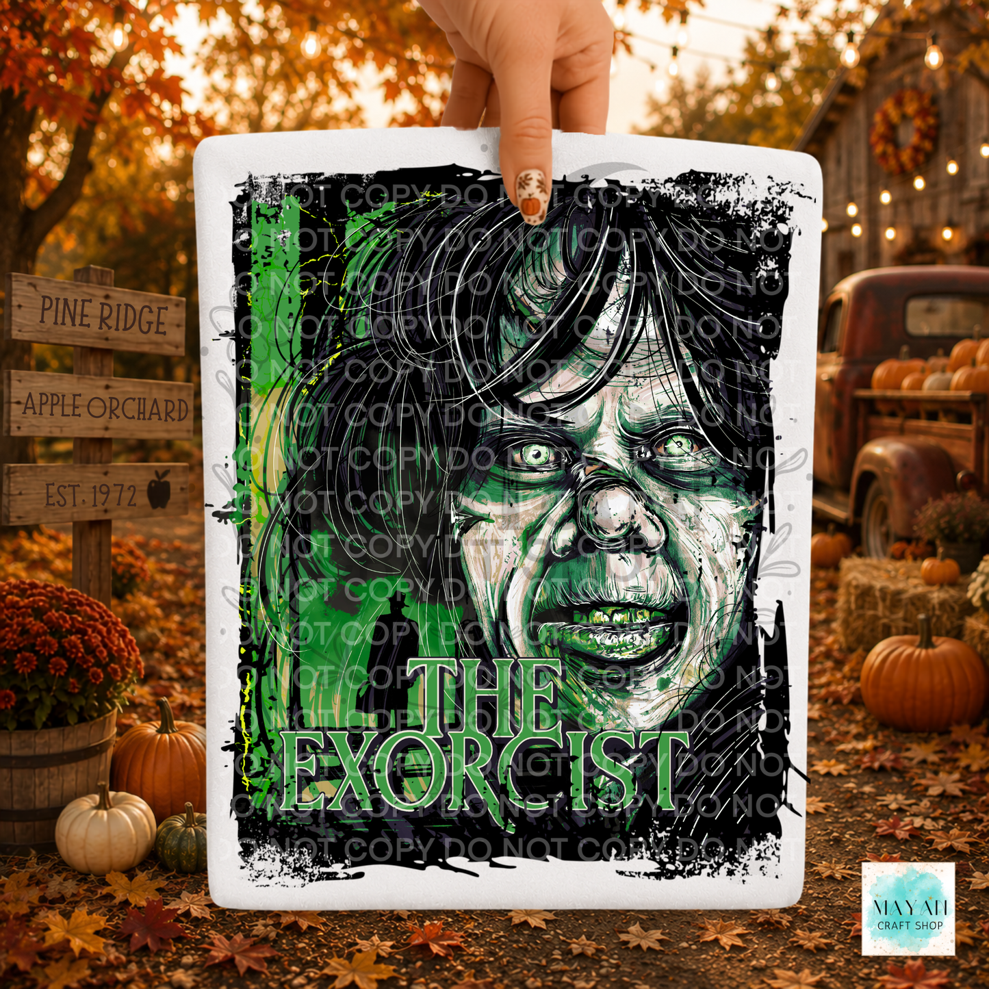A hand holds a white shirt featuring a stylized horror portrait of a woman in green. 