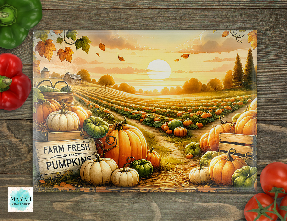 A cutting board featuring an autumn farm field with rows of pumpkins and gourds, a sunset sky, and a sign reading 'FARM FRESH PUMPKINS.' The sign is photographed on a rustic wood surface with decorative red and green peppers around it.