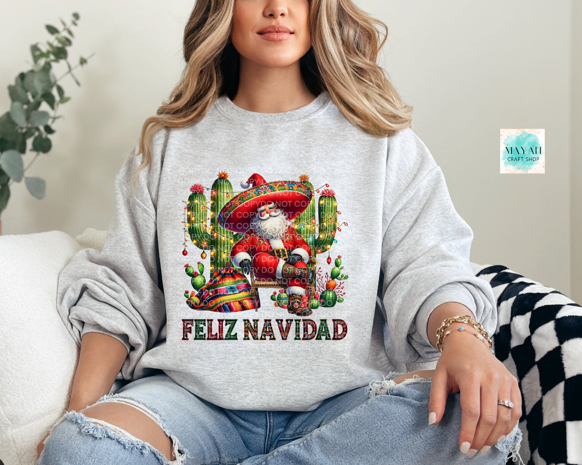 Person wearing a gray sweatshirt with a festive design and 'Feliz Navidad' text.