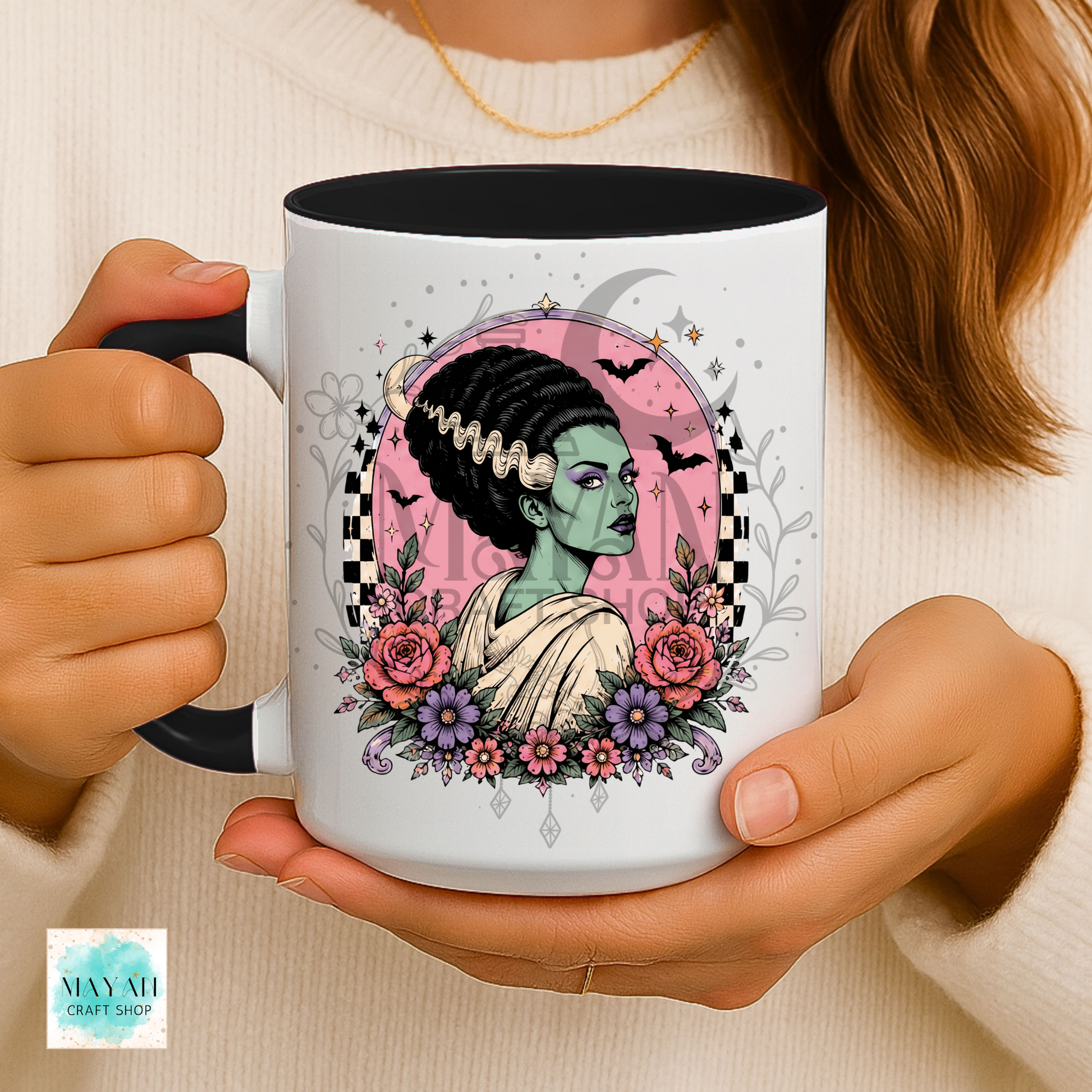 Person holding a mug with a decorative design of a woman with flowers and bats.