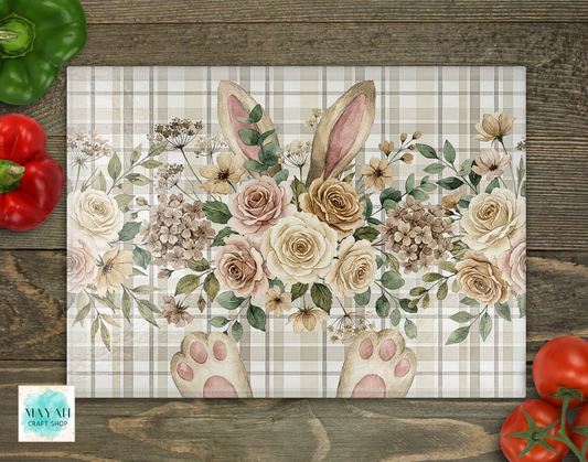 Floral design with bunny ears and paw prints on a plaid background, placed on a wooden surface with vegetables.