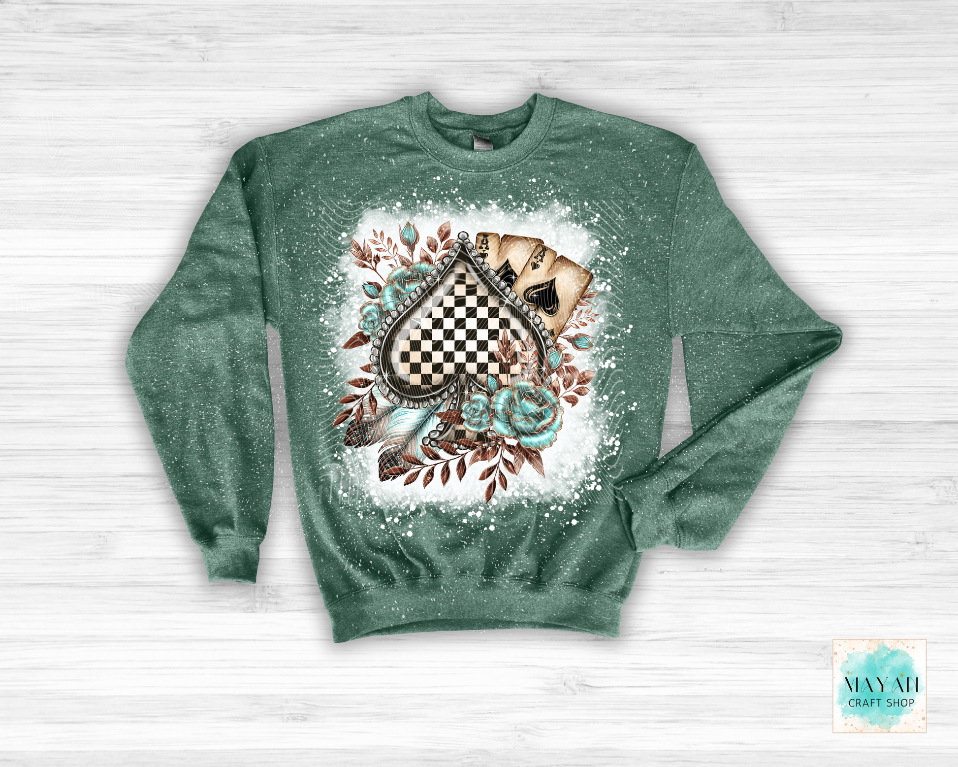 Green sweatshirt with a decorative design on a white wooden surface