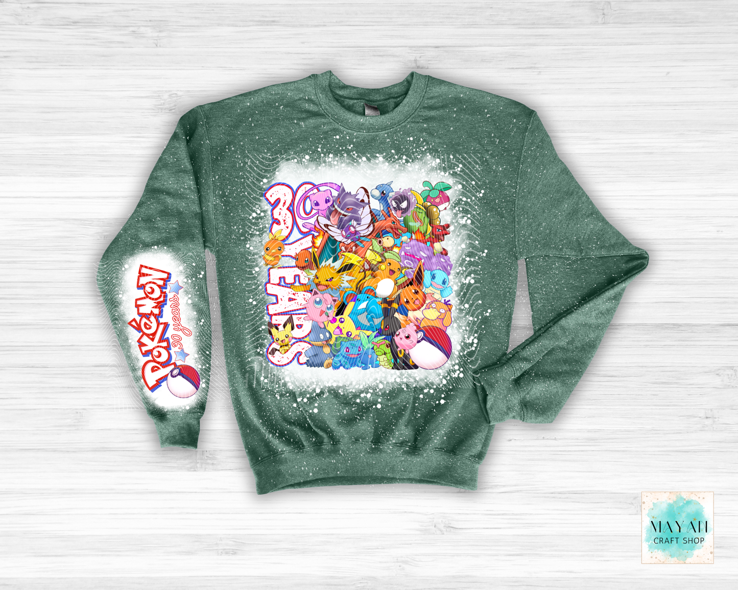 Green sweatshirt with colorful graphic design on a white wooden background