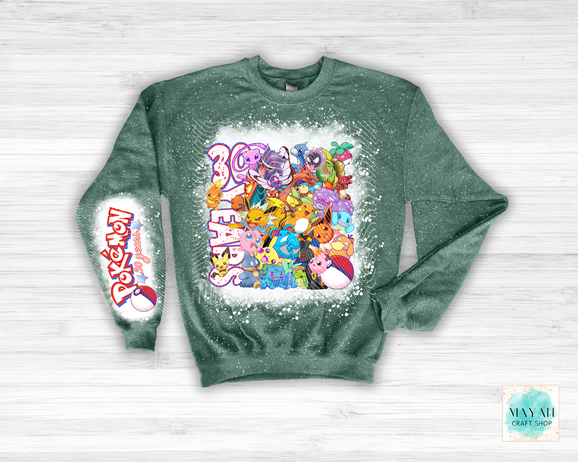 Green sweatshirt with colorful graphic design on a white wooden background