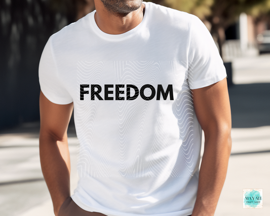 Person wearing a white t-shirt with 'FREEDOM' printed on it, standing outdoors.
