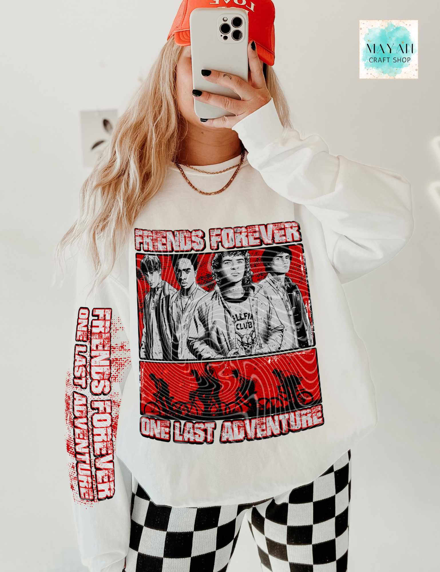 Person wearing a sweatshirt with a graphic design and text, taking a selfie.