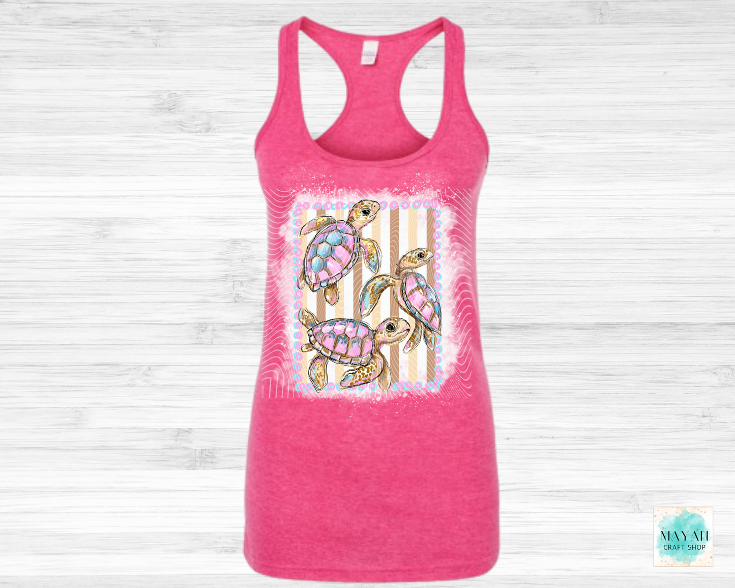 Pink tank top with a colorful turtle design on a light wooden background