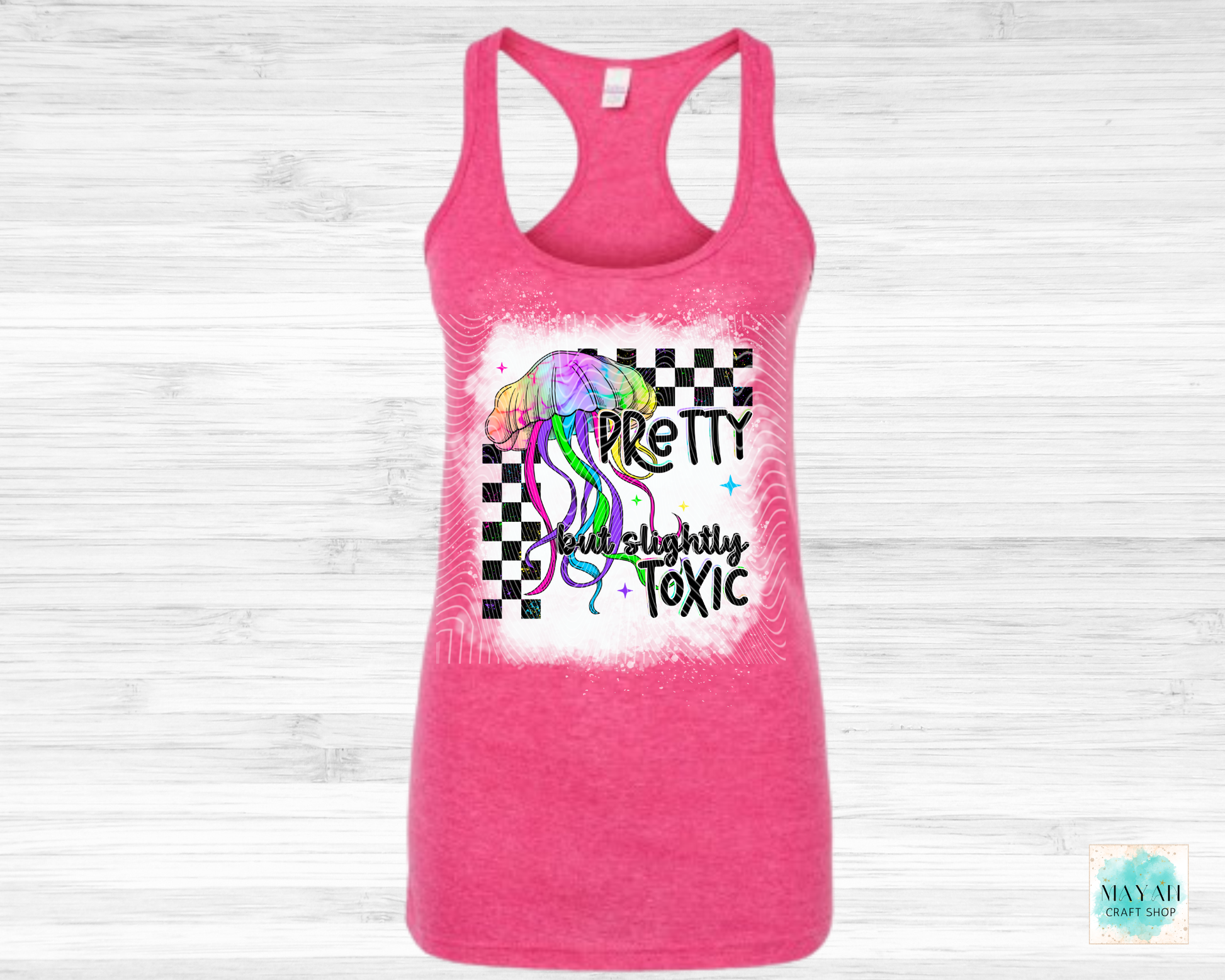 Pink tank top with colorful graphic and text on a light wooden background