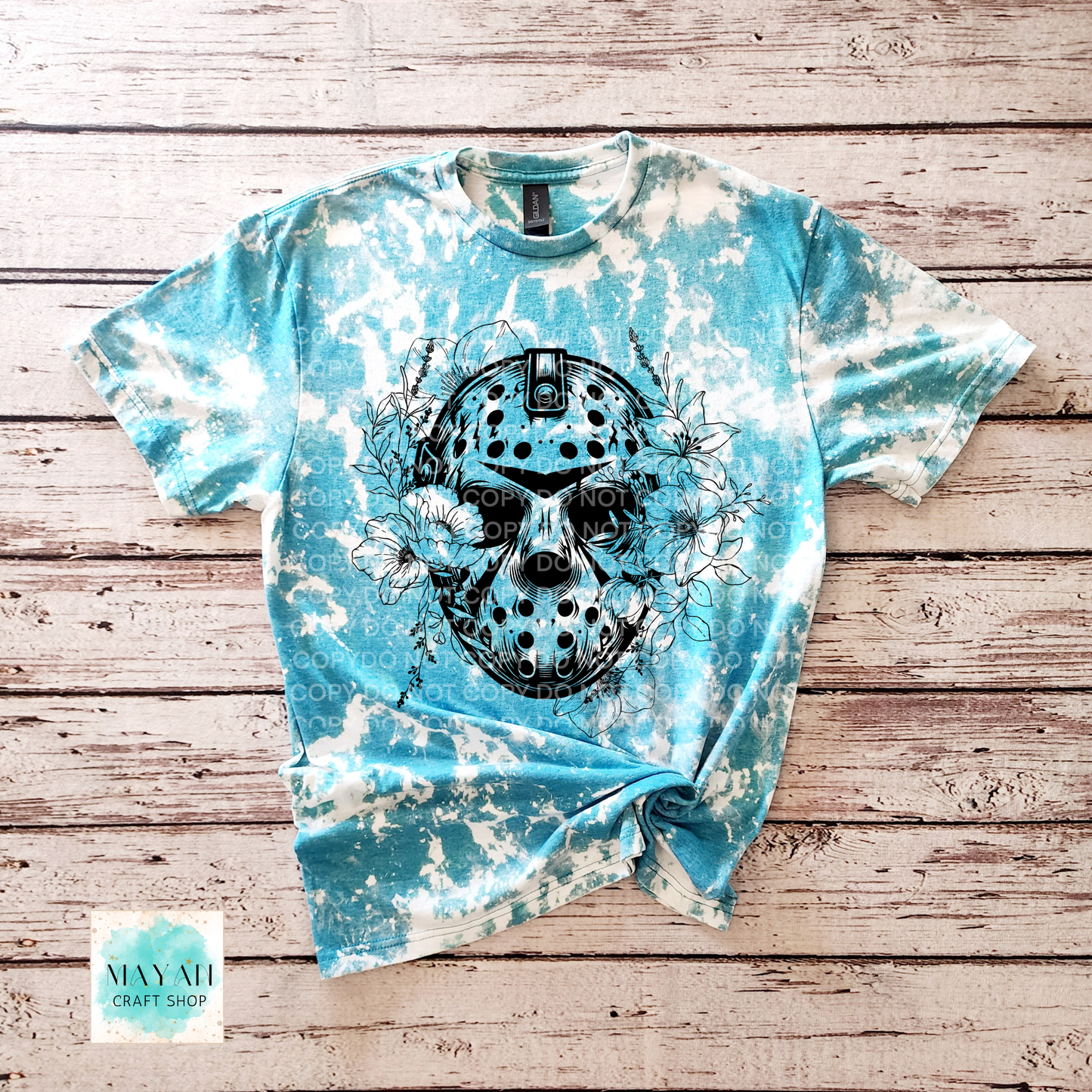 Blue tie-dye t-shirt with a black graphic design on a wooden surface, featuring the brand 'Mayah Craft Shop'.