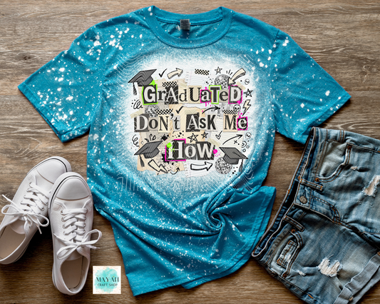 Blue t-shirt with graduation-themed design on a wooden surface with white sneakers and denim shorts.