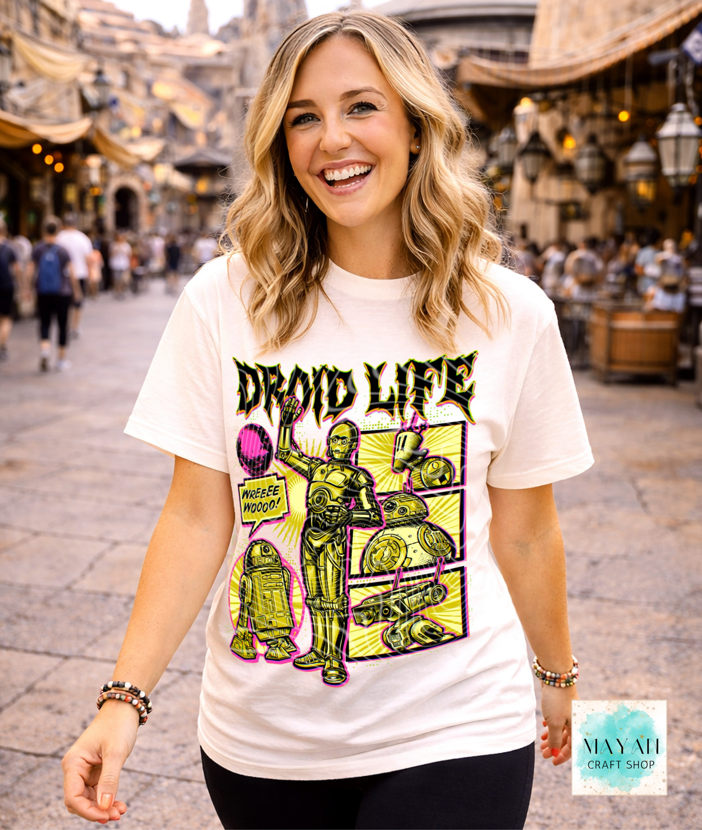 Woman wearing a 'Droid Life' t-shirt with a robot graphic in an outdoor setting.