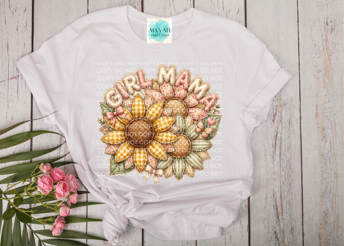 White t-shirt with a sunflower design and 'Girl Mama' text on a wooden surface.