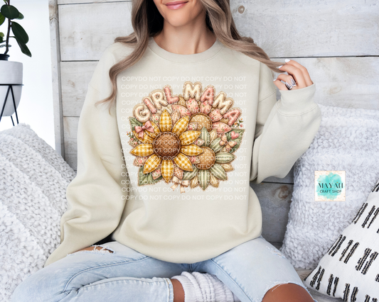 Woman wearing a cream sweatshirt with a sunflower design and 'Girl Mama' text, sitting on a couch.