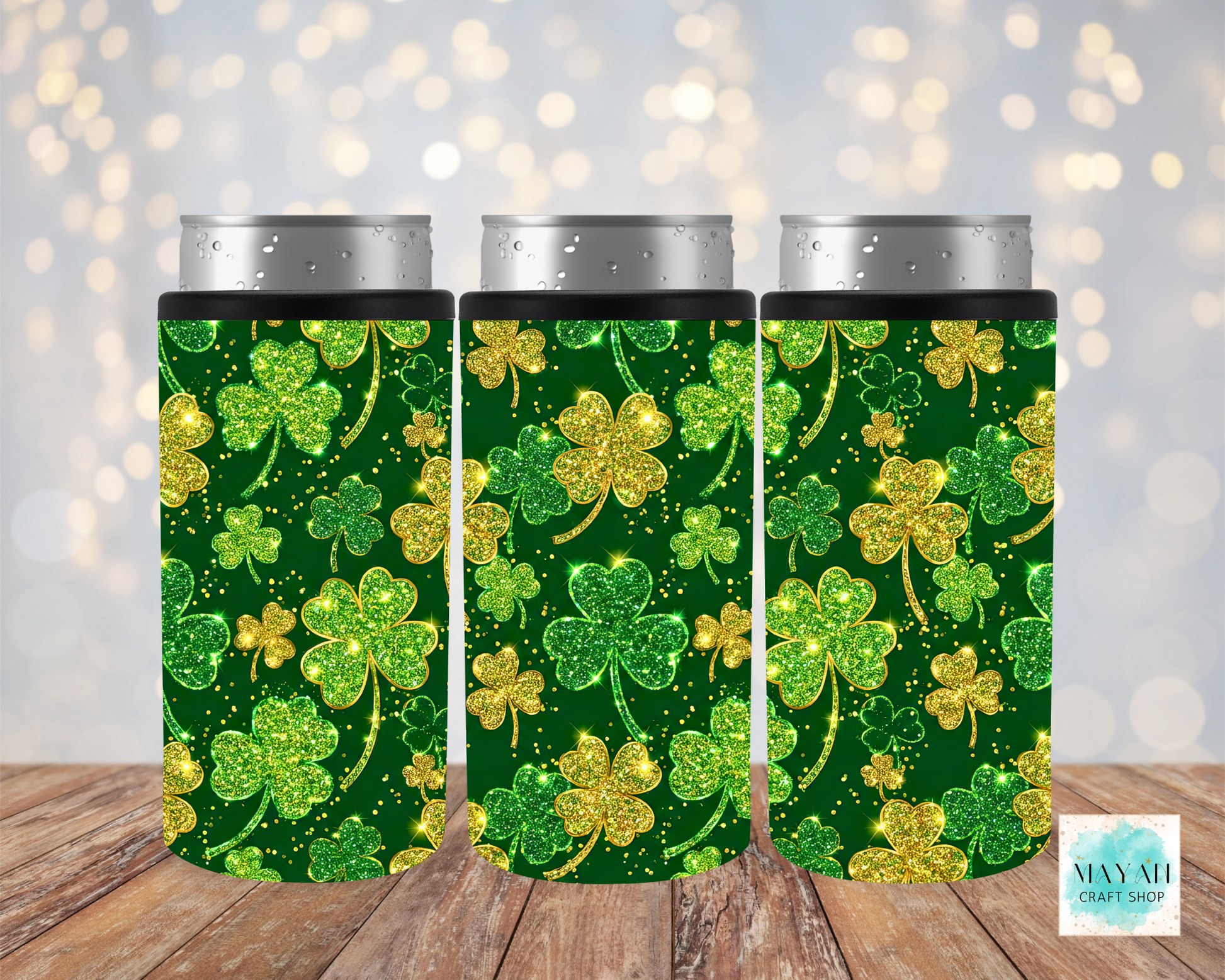 Three green can coolers with gold shamrock patterns on a wooden surface.