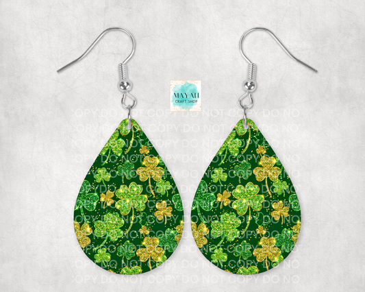 Teardrop-shaped earrings with green shamrock pattern on a white background