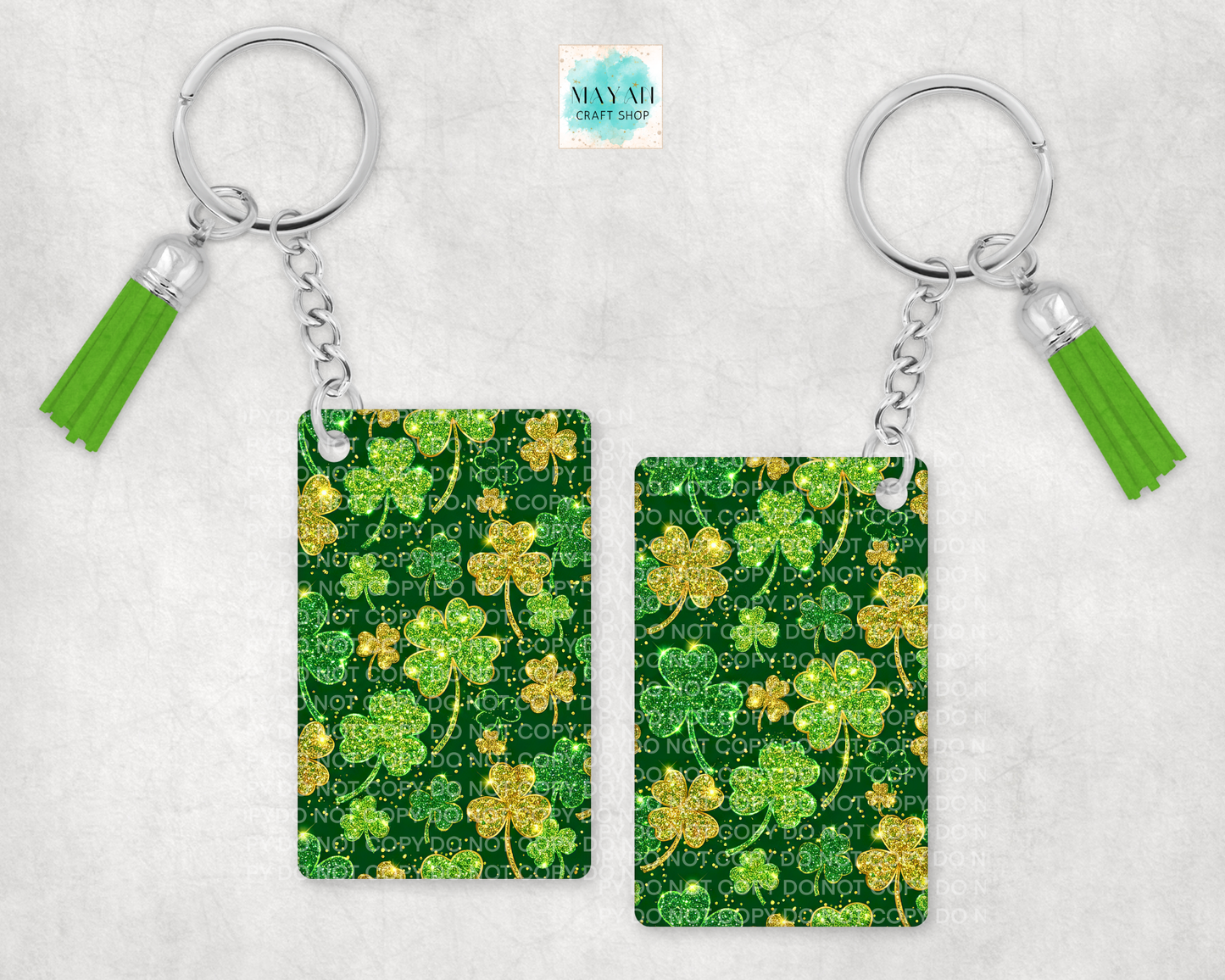 Two keychains with shamrock patterns and green tassels on a light gray background.