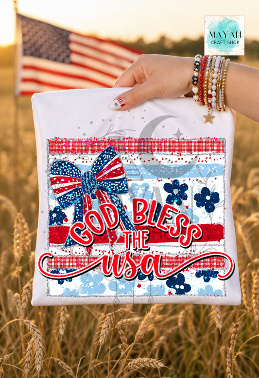 Hand holding a small pouch with 'God Bless the USA' text and American flag design, set against a blurred natural background.
