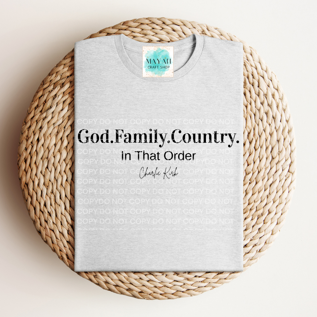 Gray t-shirt with text 'God. Family. Country. In That Order' on a woven mat, with a brand logo in the corner.