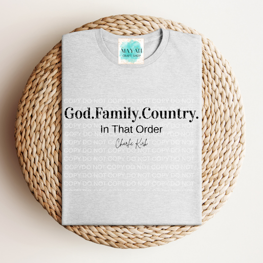 Gray t-shirt with text 'God. Family. Country. In That Order' on a woven mat, with a brand logo in the corner.