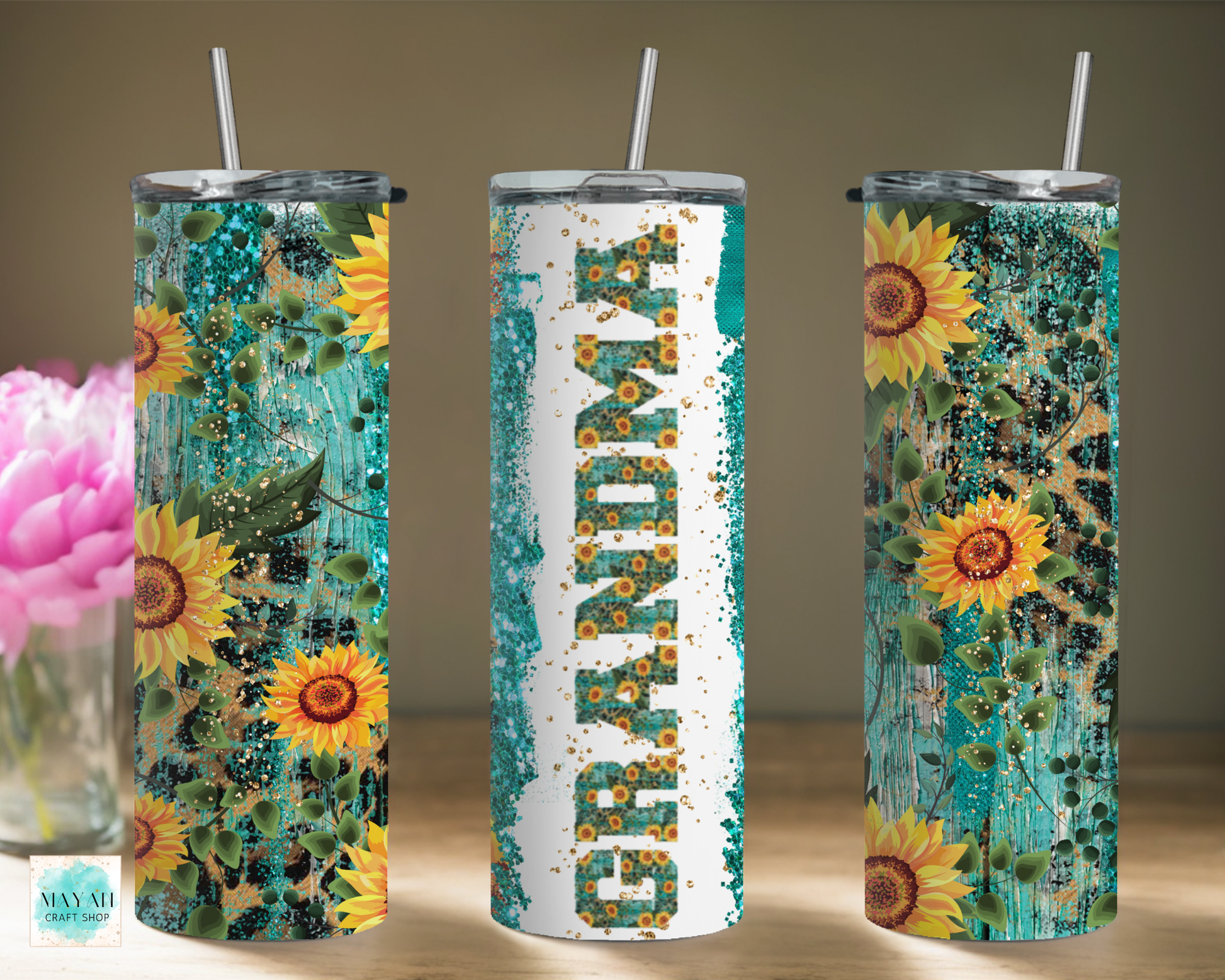 Three sunflower-themed tumblers with straws on a wooden surface.
