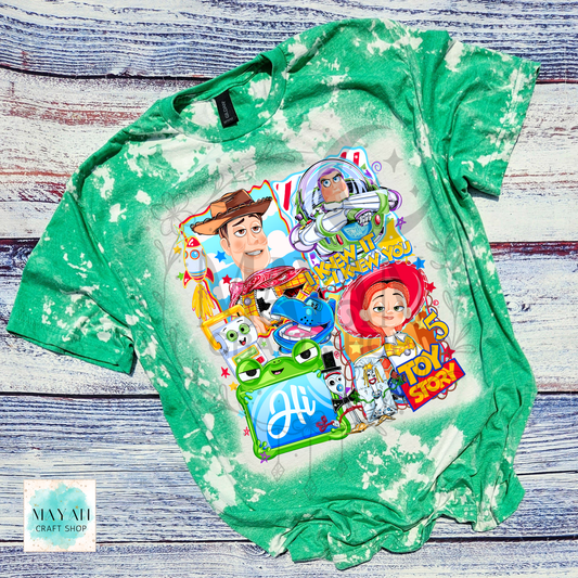 Green tie-dye t-shirt with character graphics on a wooden surface