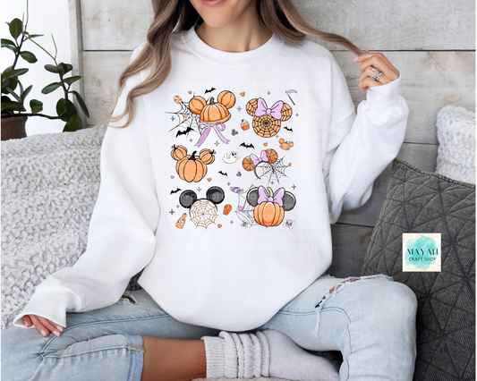 Person wearing a white sweatshirt with Halloween-themed designs, sitting on a couch.