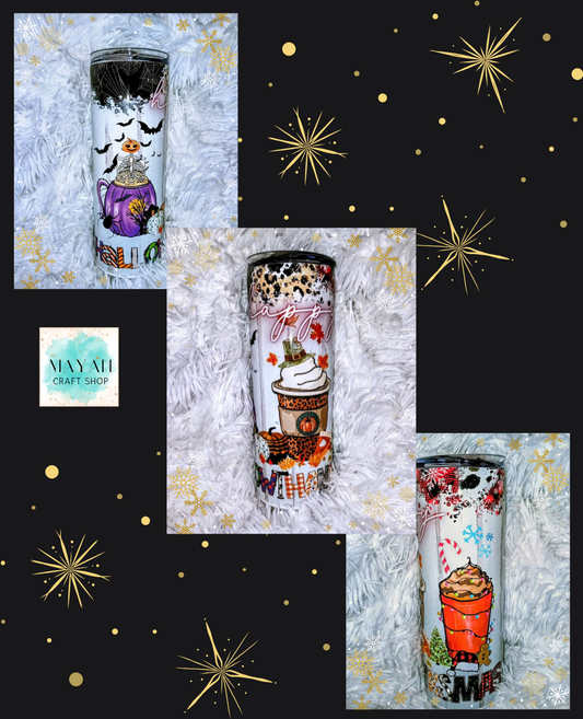 Three insulated tumblers with Halloween-themed illustrations are arranged in a collage on white faux fur with gold starburst graphics on a black background. The tumblers feature designs including a witch, a pumpkin spice latte, and a hot cocoa drink.