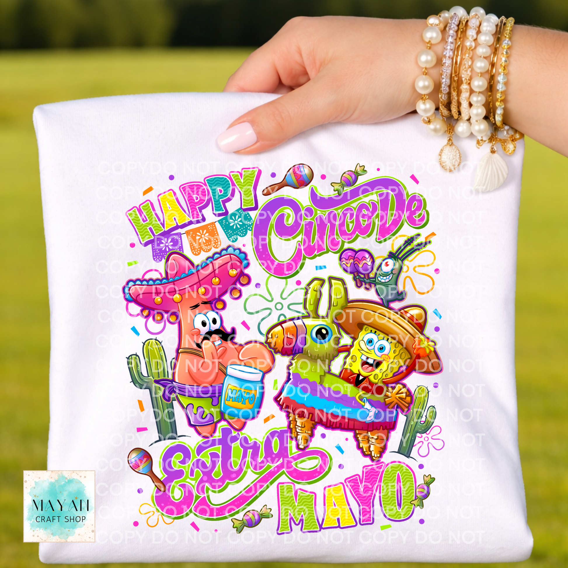Hand holding a white pillow with colorful 'Happy Cinco De Mayo' design featuring cartoon characters.