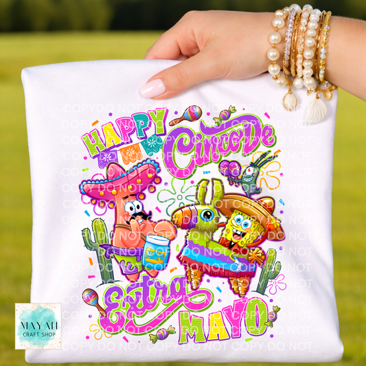 Hand holding a white pillow with colorful 'Happy Cinco De Mayo' design featuring cartoon characters.