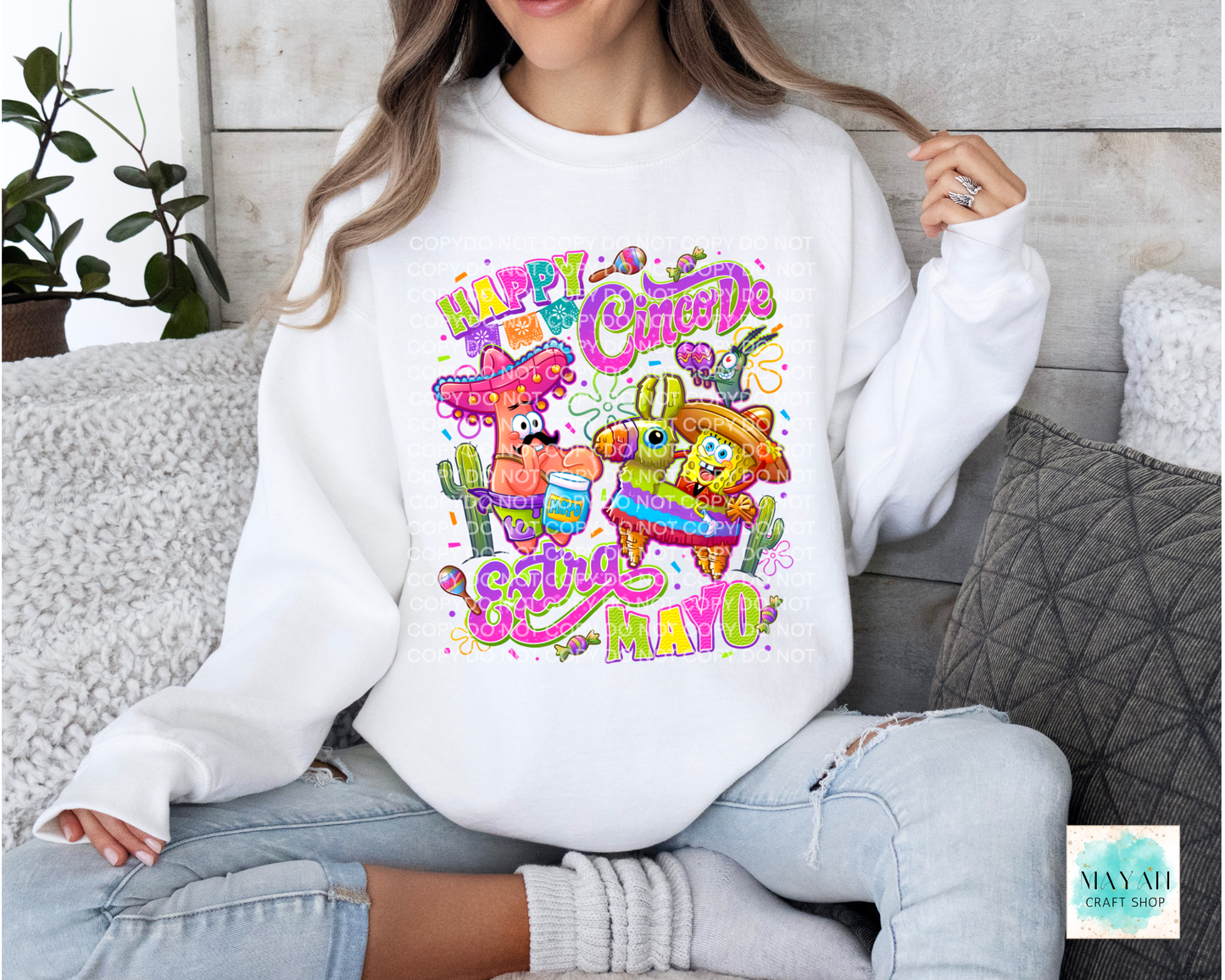 Person wearing a white sweatshirt with colorful Cinco de Mayo design sitting on a couch.
