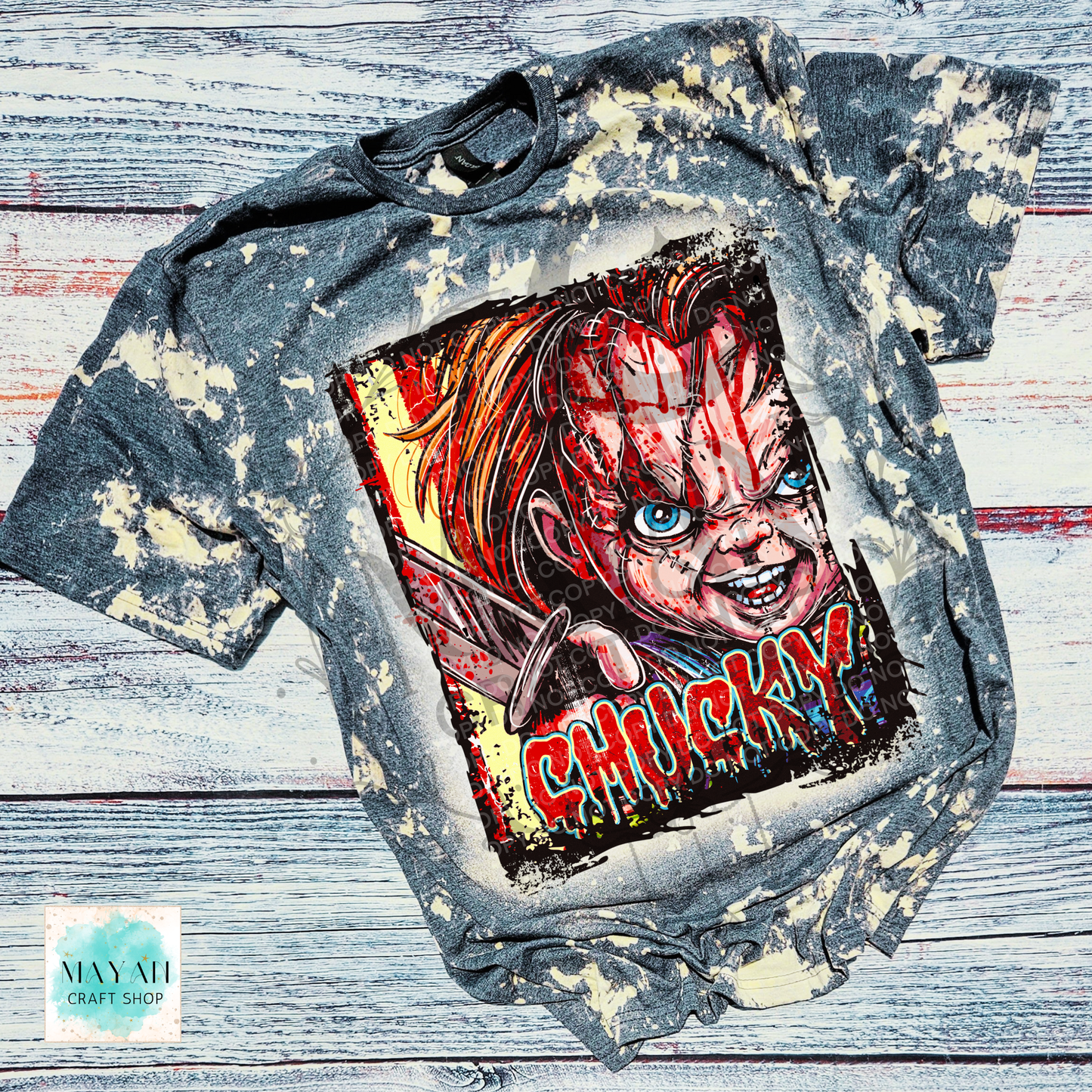 A short-sleeve graphic T-shirt laid flat on a rustic whitewashed wood surface. The shirt is charcoal gray with a bleached, distressed finish and features a large front print with red blood, blue eyes, and a text in red dripping letters.