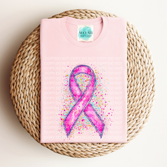 Pink tshirt with a colorful pink ribbon design on a woven surface