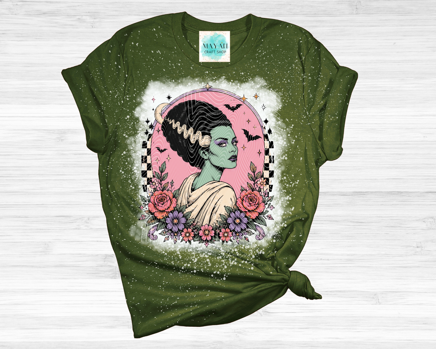 Green t-shirt with a graphic design of a woman with flowers and bats on a white background