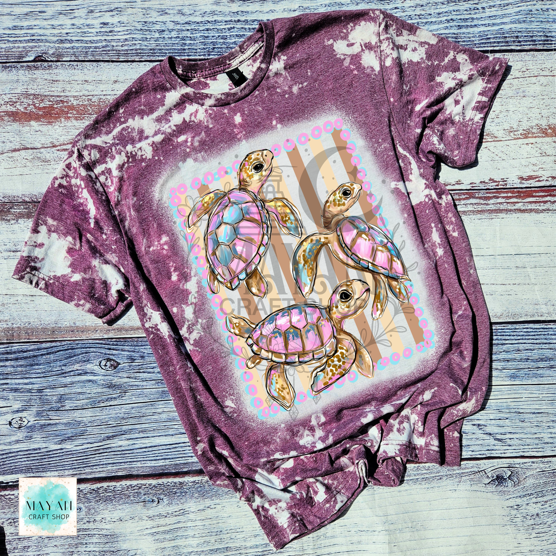 Bleached purple t-shirt with colorful turtle design on a wooden surface